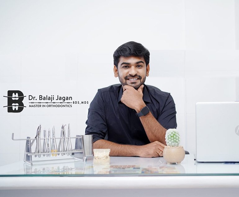Dr. Balaji Jagan at his clinic desk with orthodontic instruments — dental clinic in Pollachi, Coimbatore
